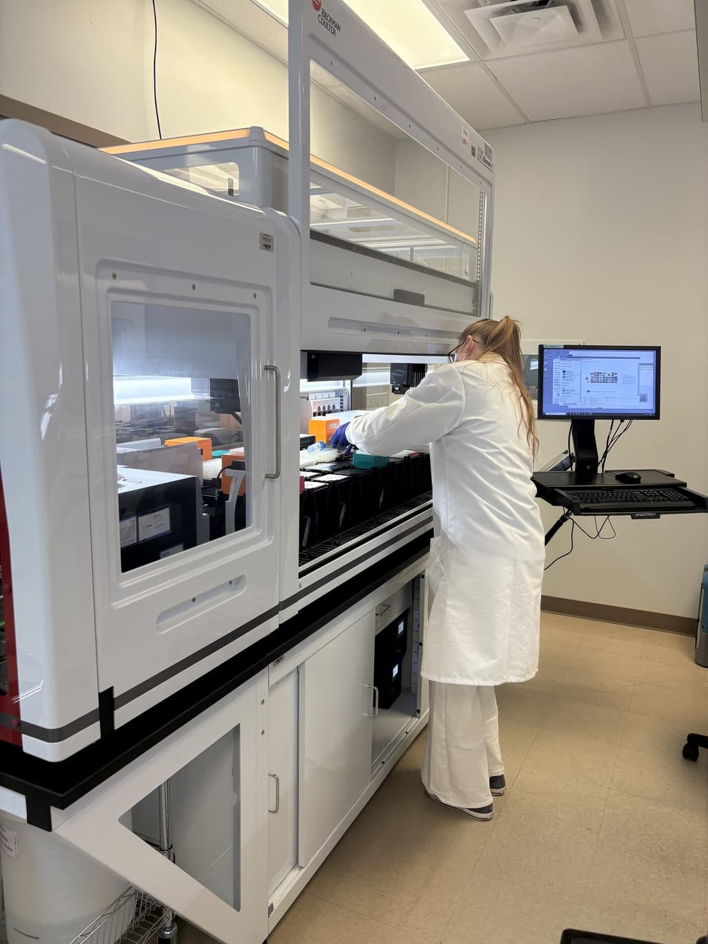 A Helio Genomics scientist in a white lab coat working at an automated laboratory instrument