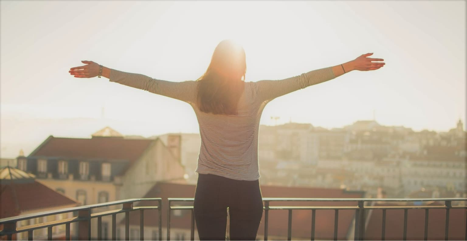 Image of female with arms wide open staring into the sunset