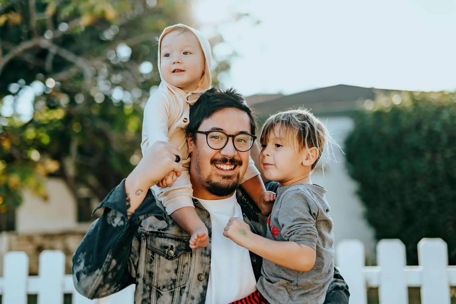 A father carrying his two young children outdoors