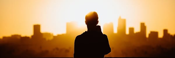 A person looking toward a city skyline at sunset