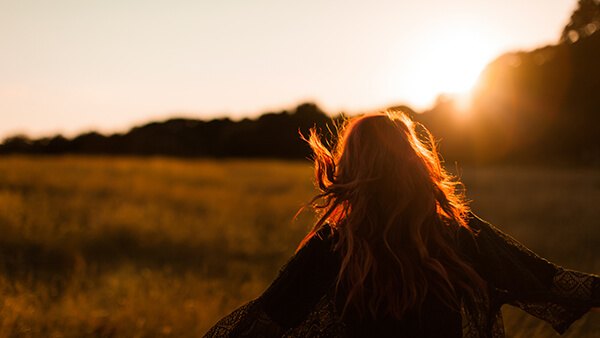A woman standing in a golden field at sunset